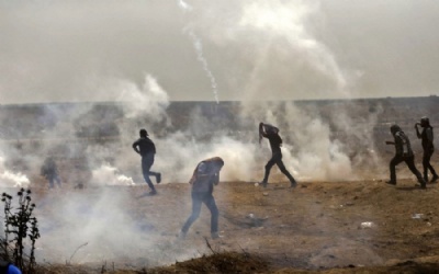 Fronteira de Gaza com Israel volta a ter confrontos  Palestinos ficam cobertos por gs lacrimogneo durante confronto com as foras de segurana israelenses nesta sexta-feira (13) (Foto: Mahmud Hams / AFP) 